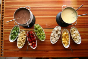 Gastronomia. Food. Sabor. Degustação. Restaurante. Fondue. Fondue de Chocolate ao Leite. Frutas. Banana. Uva. Manga. Morango.Kiwi. Fondue de Queijo. Queijos. Queijo branco. Queijo prato. Pão.